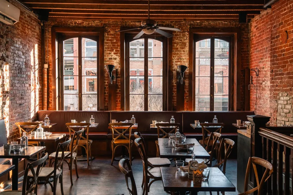 The hex-tile bar at Perro Negro Taperia — backlit bottles, pendant lights, and the dining room beyond