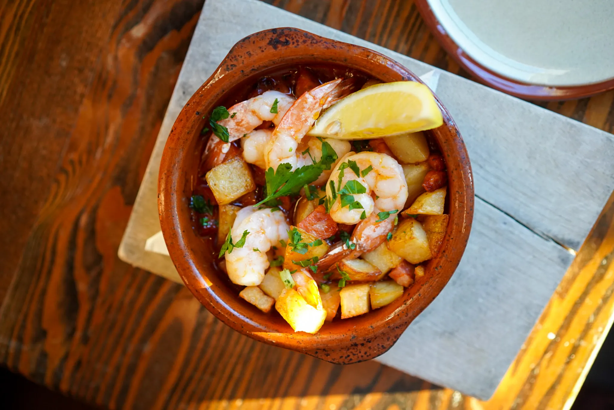 Gambas y chorizo, Spanish shrimp with chorizo and potatoes in a clay bowl, top-down