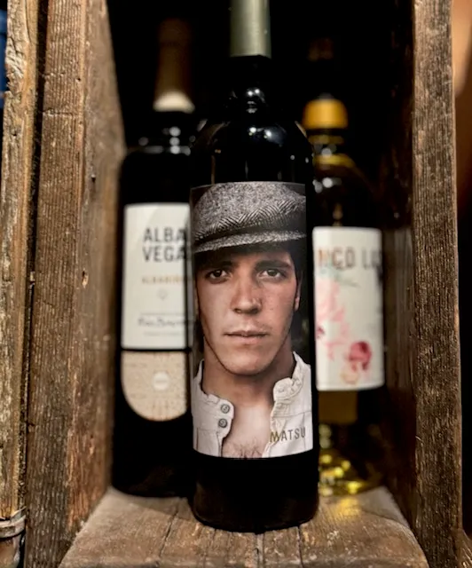 Spanish wine bottles in a wooden crate at Perro Negro Taperia — Matsu in the foreground